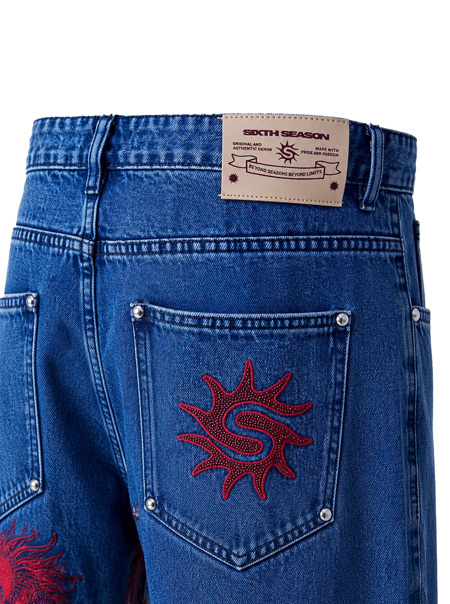 Close-up of the back waistband and pocket area of blue denim jeans. A tan leather patch at the back waist reads 'SIXTH SEASON'.